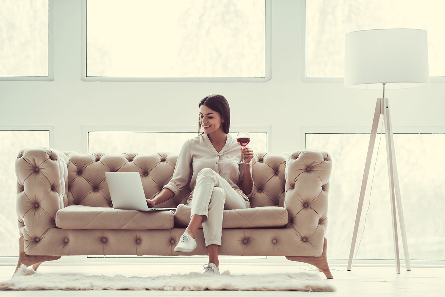 Woman drinking red wine on couch.